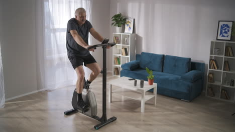 keeping-fit-and-health-for-middle-aged-people-during-self-isolation-and-pandemic-of-coronavirus-man-is-training-with-exercycle